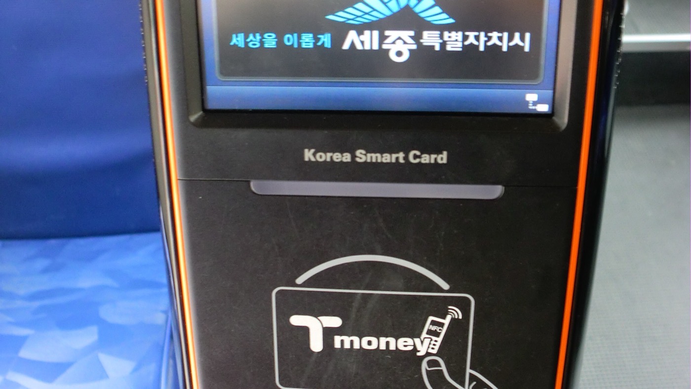 Un validador de tarjeta de transporte junto a la puerta de un autobús coreano